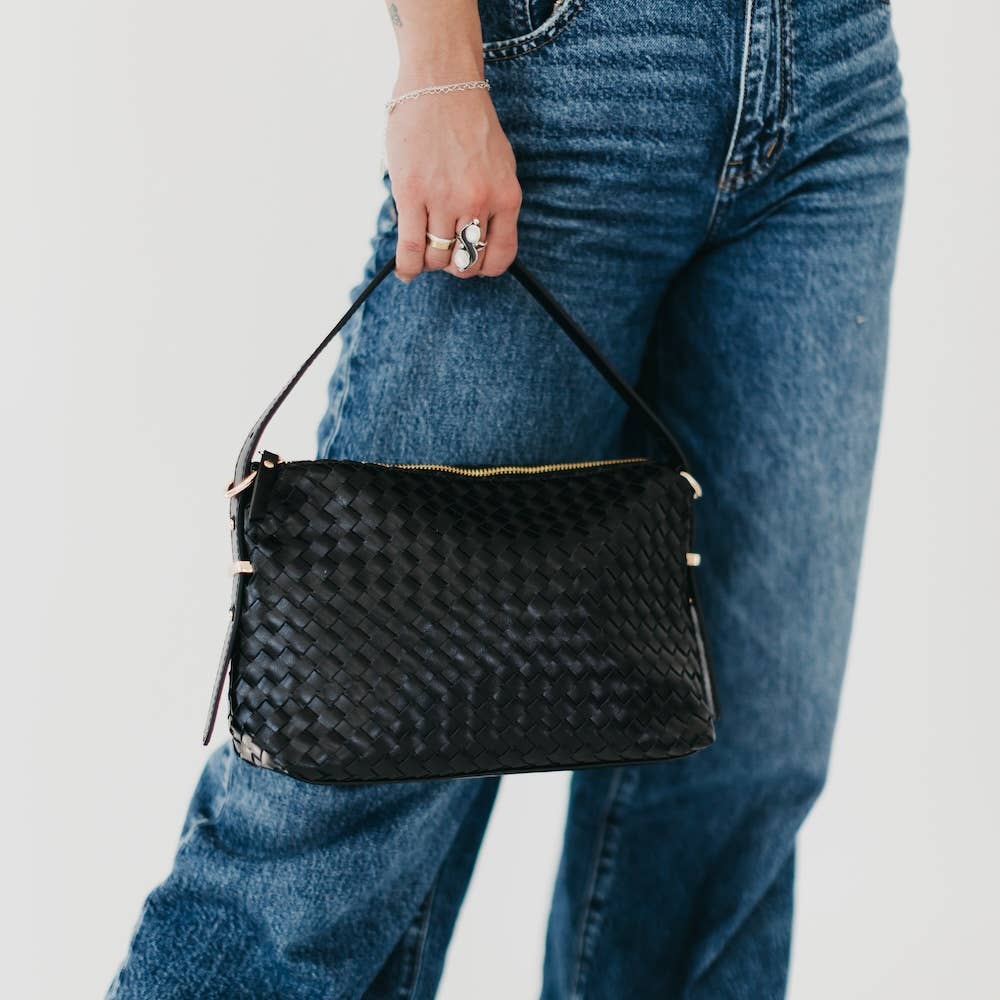 Person holding a black woven handbag 