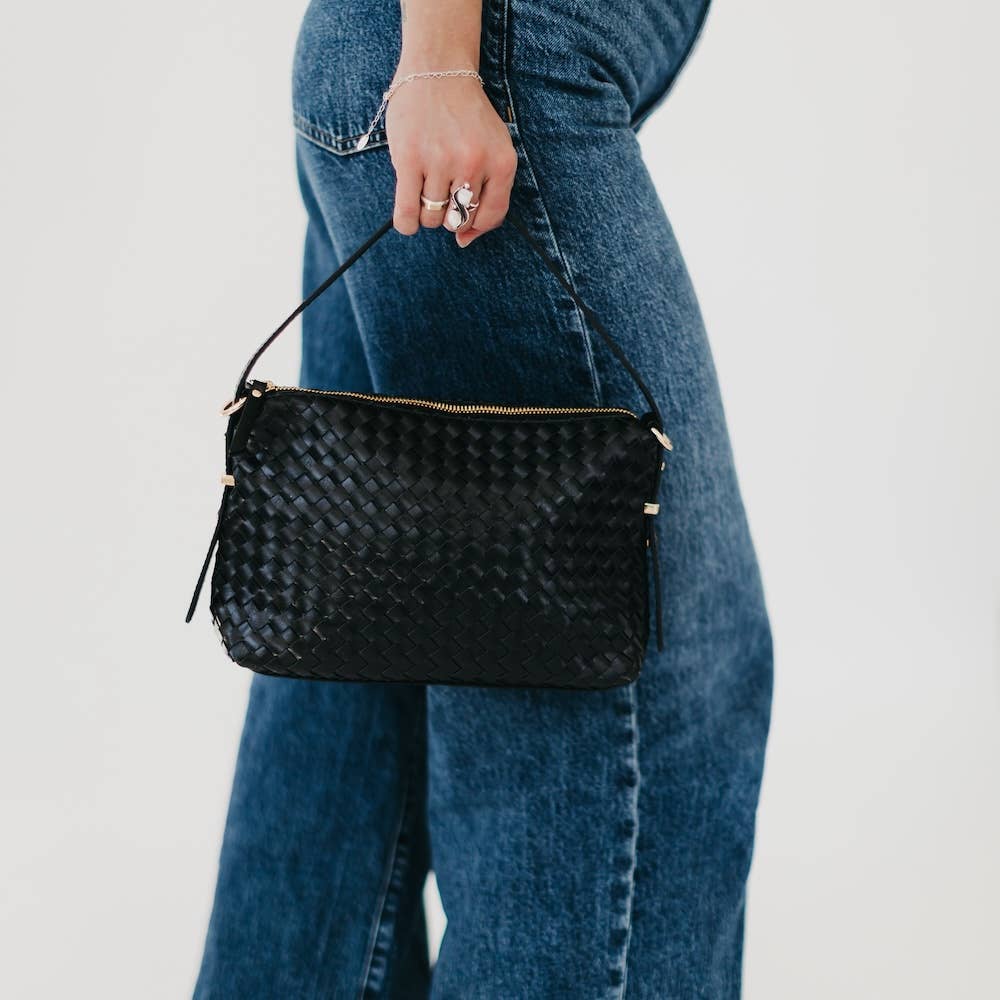 Person holding a black woven handbag 