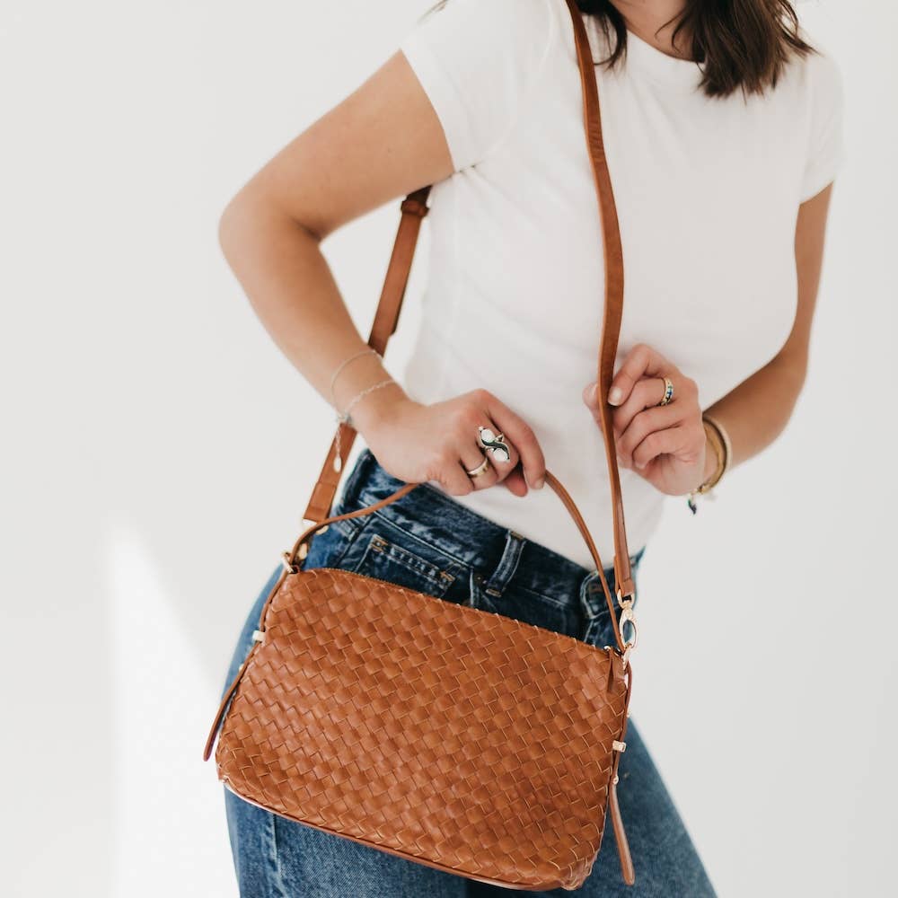 Person holding a brown woven shoulder bag