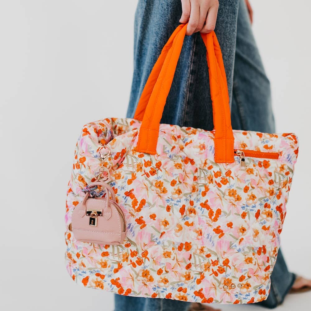 Floral tote bag with a pink purse-shaped keychain with gold lock and key design 