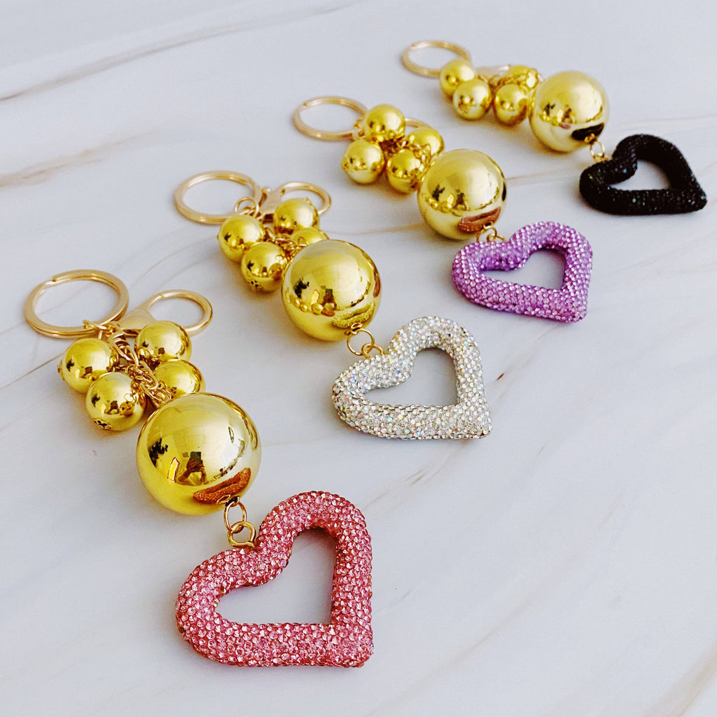 A gold-colored key chain featuring a series of round baubles and heart-shaped charms with rhinestone embellishments.