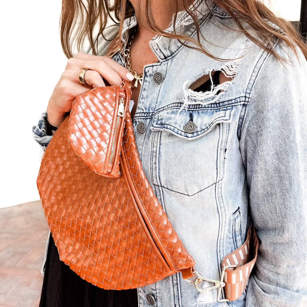 Person holding an brown woven handbag with a mini brown zipppered charm