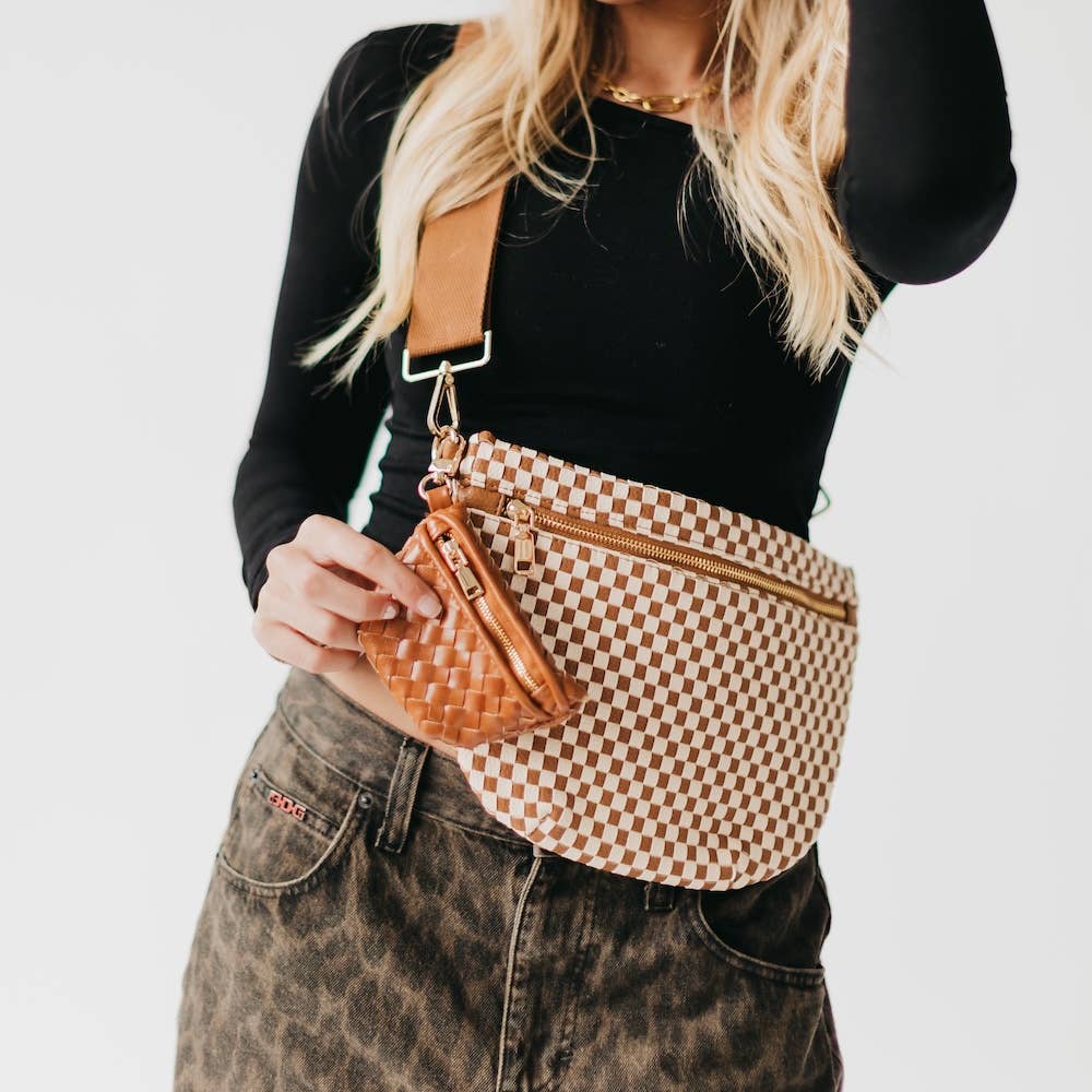 Person wearing a checkered crossbody bag with a brown mini zippered bag charm
