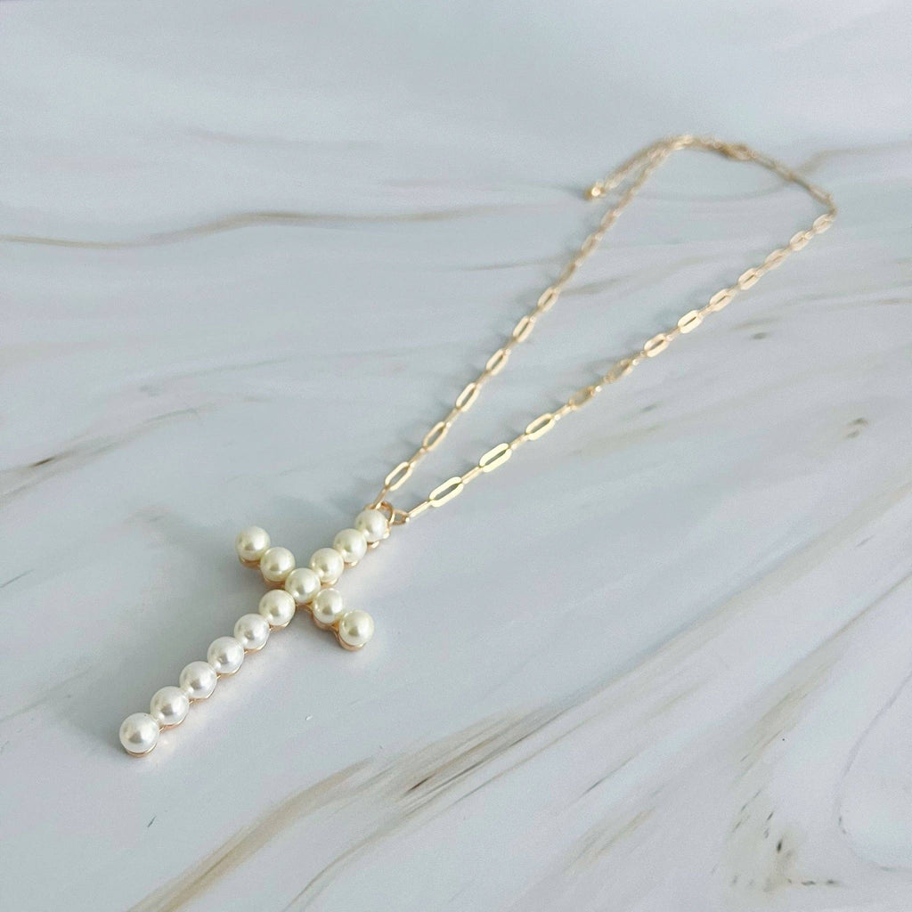 Pearl cross necklace on a marble surface