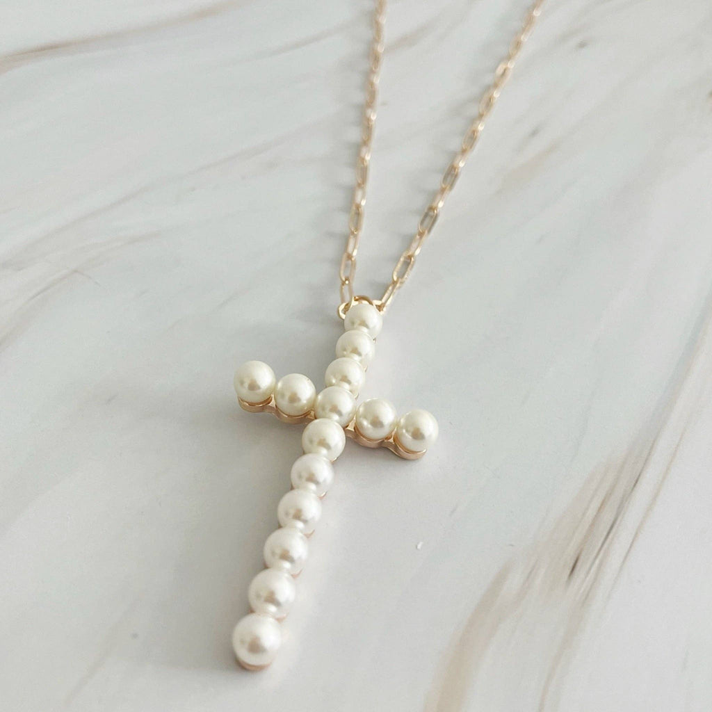 Pearl cross necklace on a marble surface
