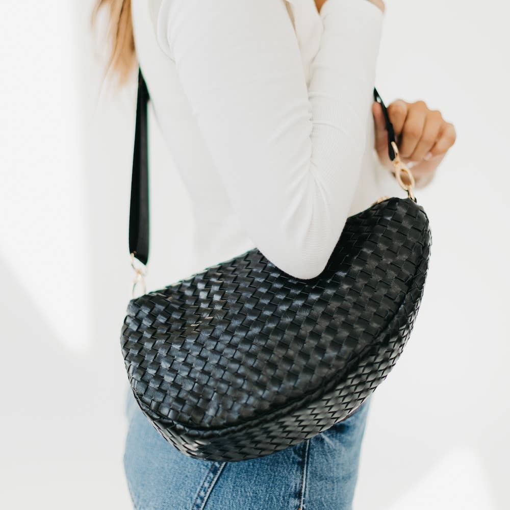 Person holding a black woven bag 