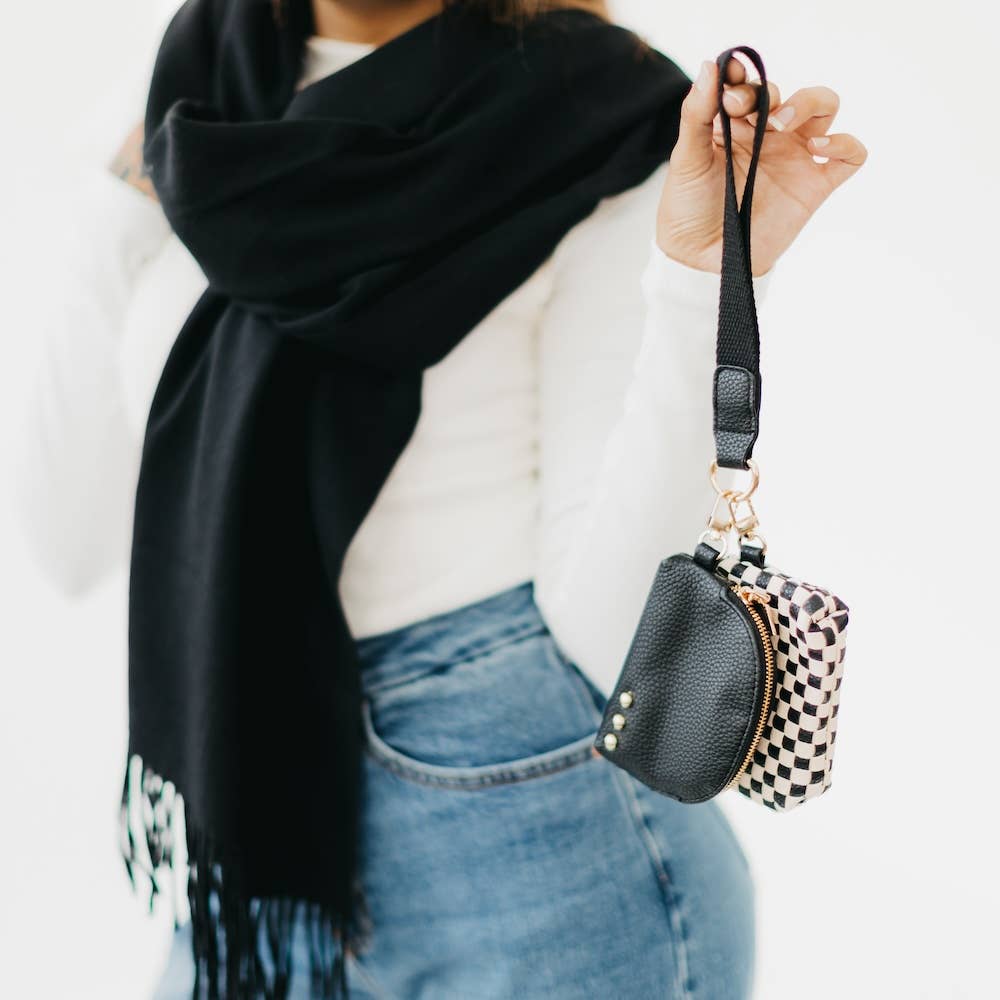 A person holding a black and white checkered wristlet with dual pouches.