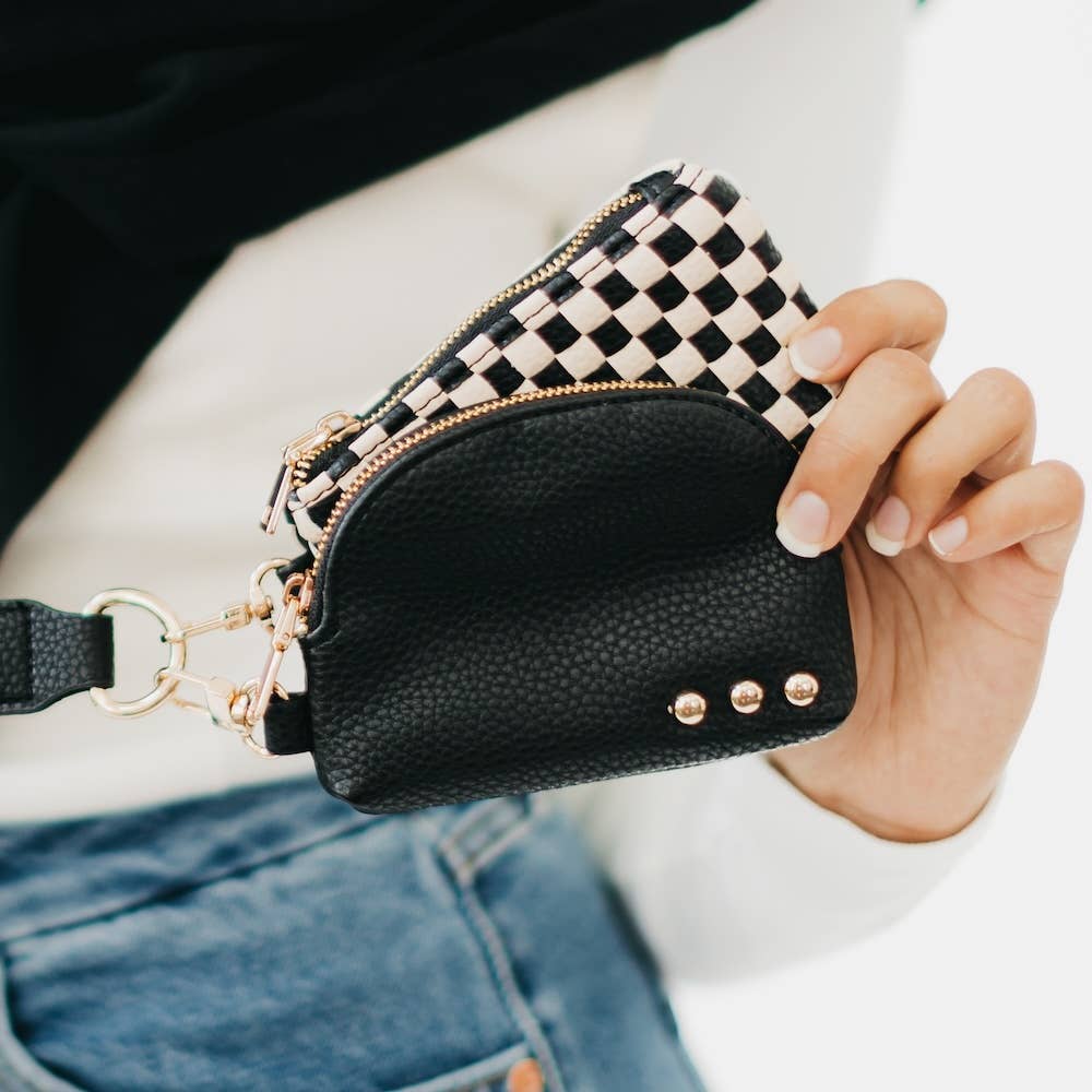 A person holding a black checkered wristlet with dual pouches.