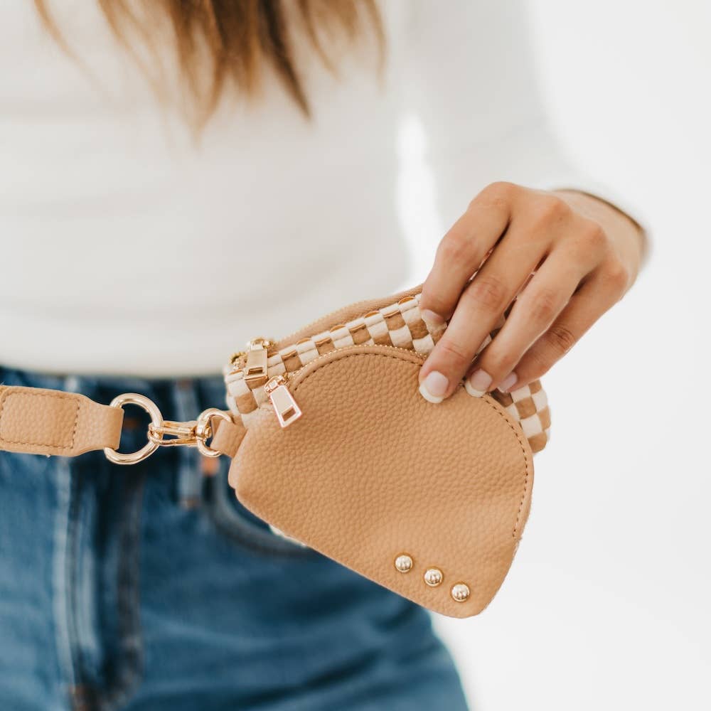 A person holding a beige wristlet pouch with a curved design and gold zipper.